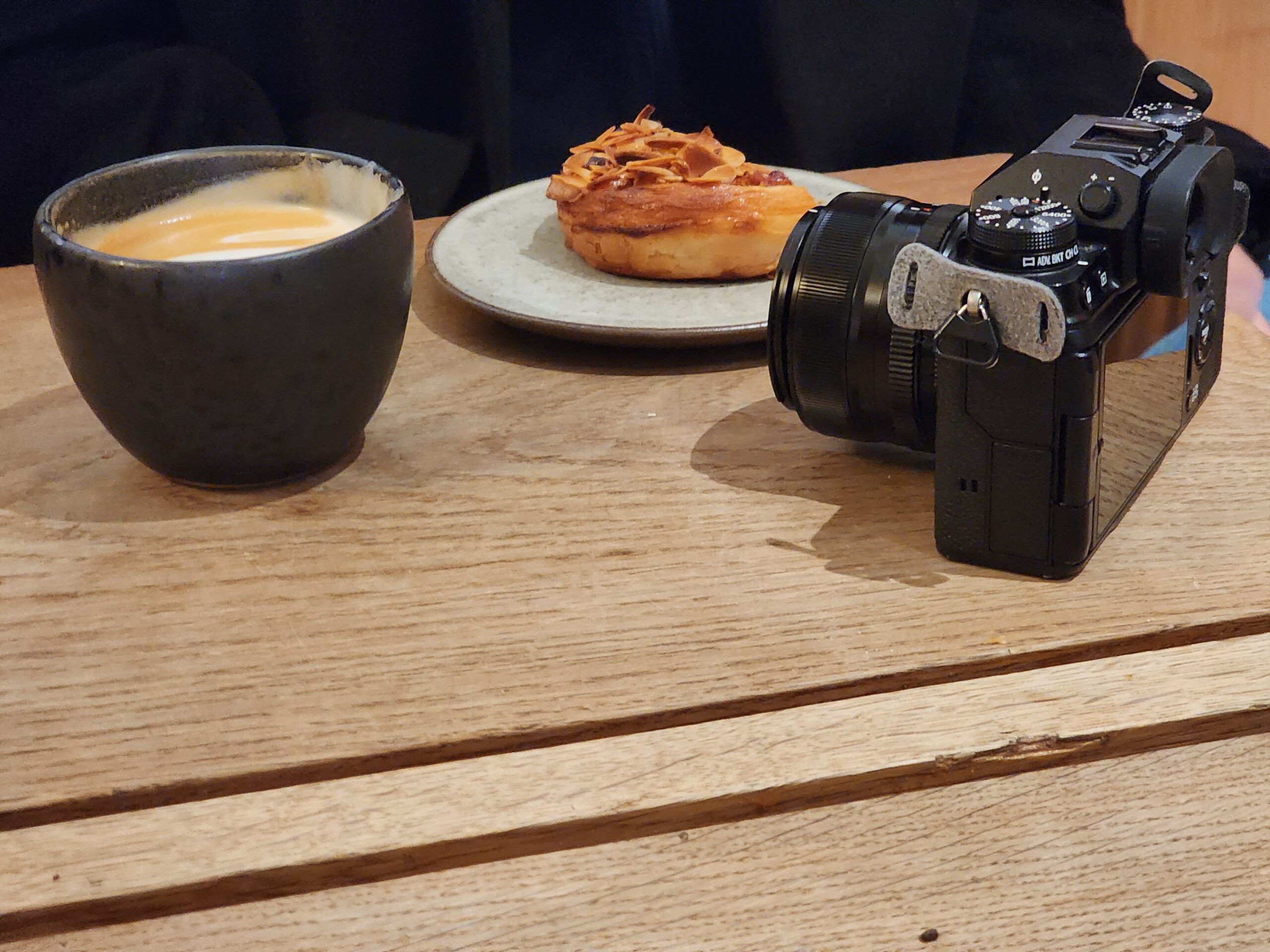 Flat White and Almond Pastry Beside a Mirrorless Camera